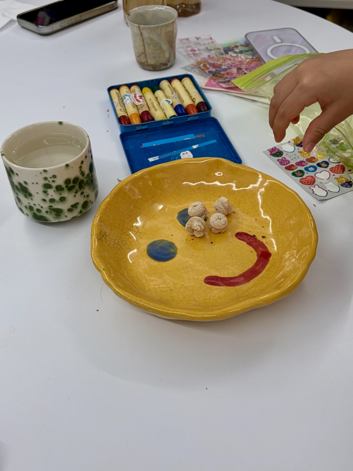 A work table set with crayons, stickers, and ceramic tableware 크레파스와 스티커, 도자기 식기가 놓여 있는 작업 테이블