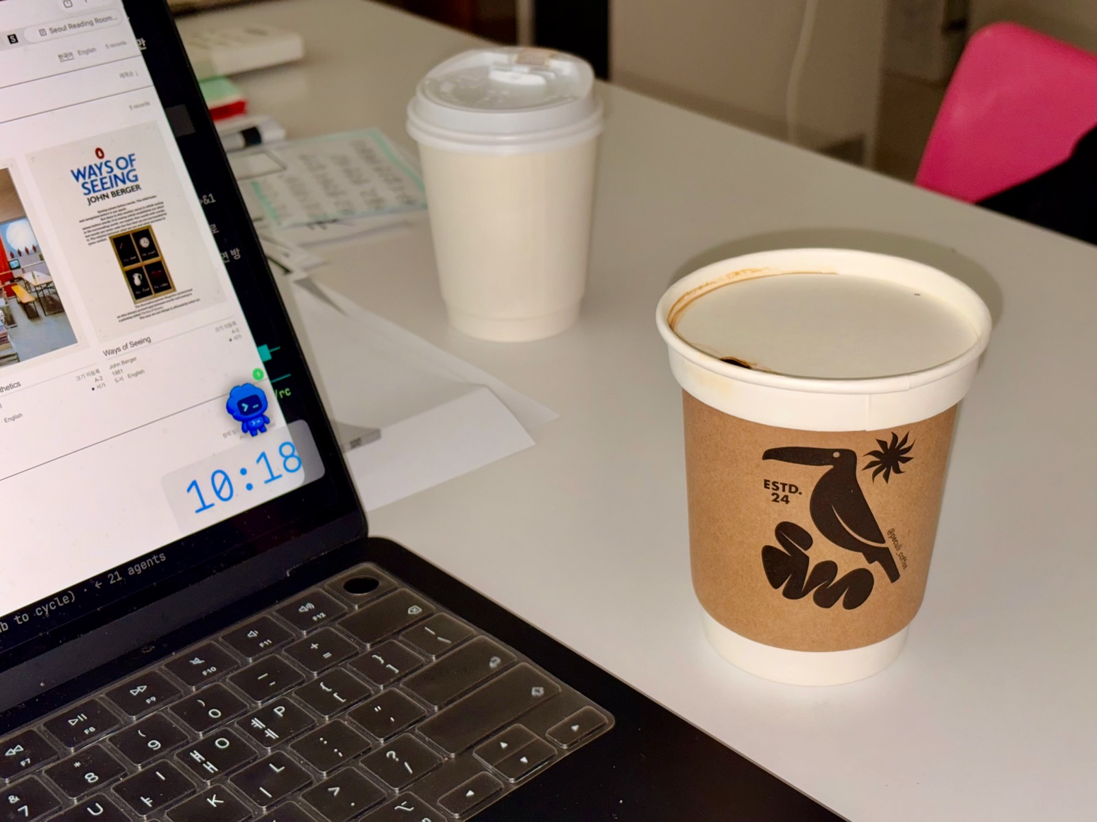 A warm latte from Peculi Coffee set on a desk with a laptop. 노트북이 놓인 책상 위에 올려진 페쿨리 커피의 따뜻한 라떼.