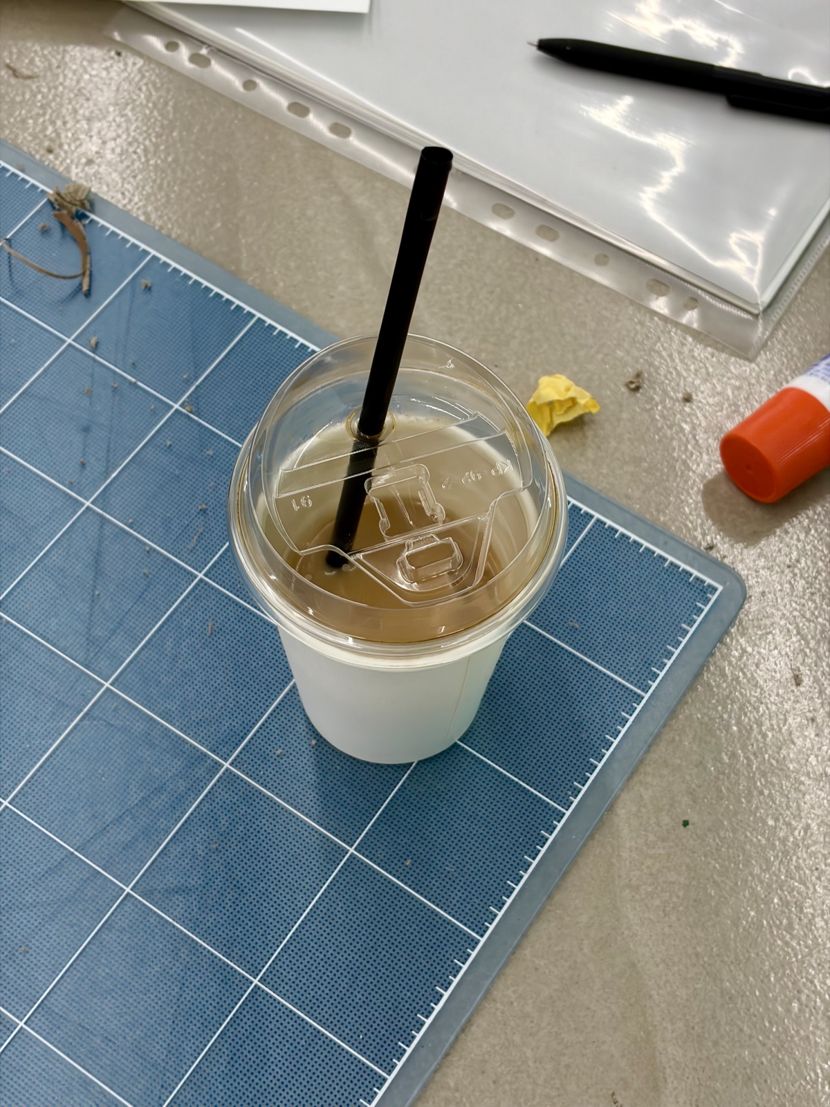 An iced latte with a black straw on a blue cutting mat 파란색 커팅 매트 위에 놓인 검은 빨대가 꽂힌 아이스 라떼