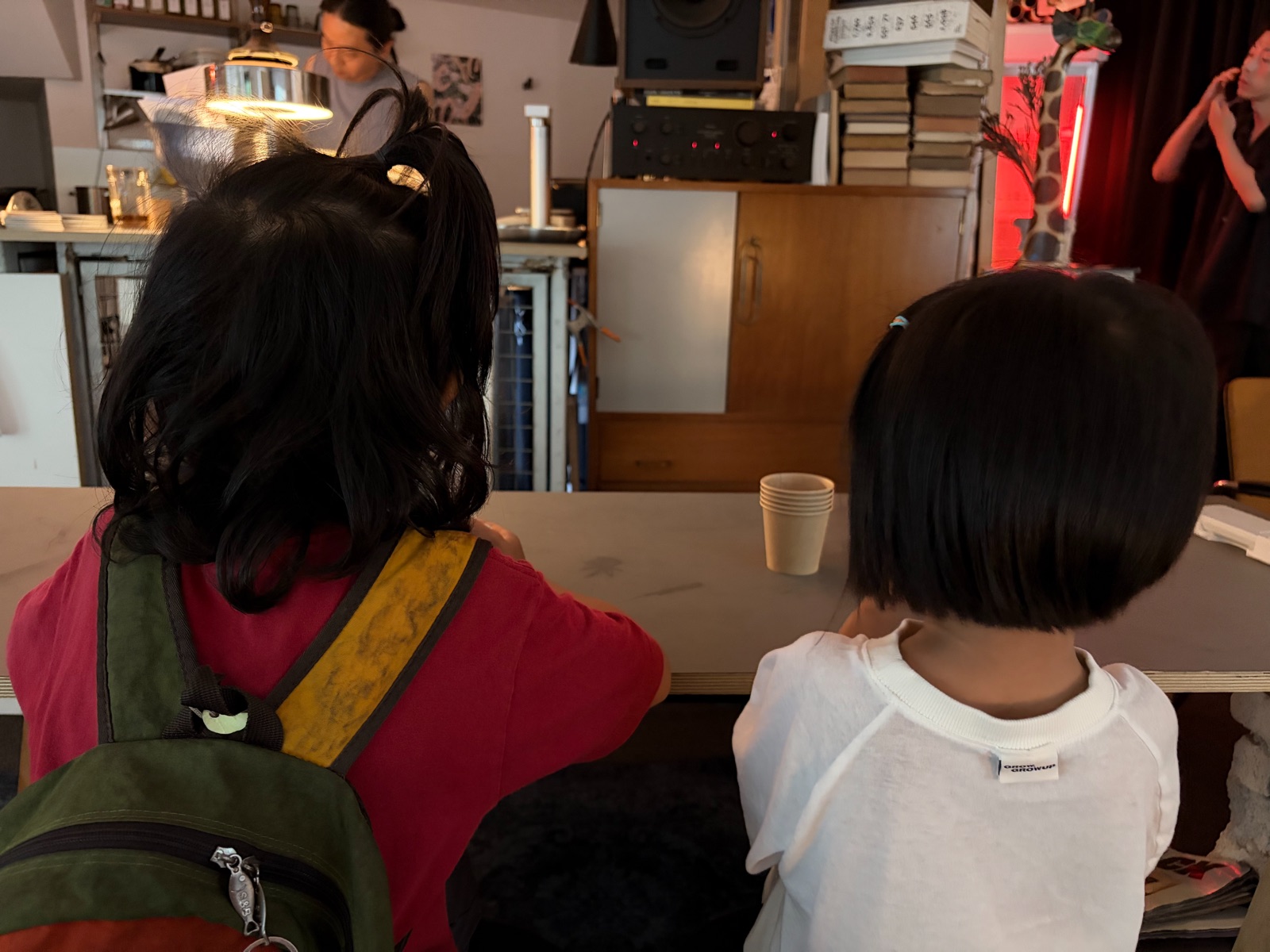 Two children sitting side by side at a cafe counter table 카페 카운터 테이블에 나란히 앉아 있는 두 아이의 모습