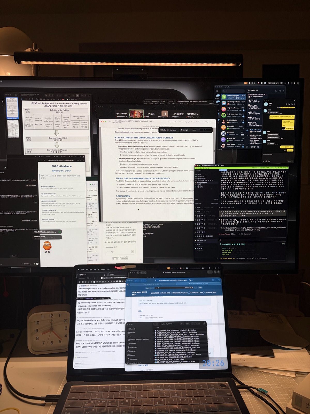 A workspace desk with a monitor light, a laptop, and several monitors arranged on it 모니터 조명과 노트북, 그리고 여러 모니터가 배치된 작업 공간 책상의 모습